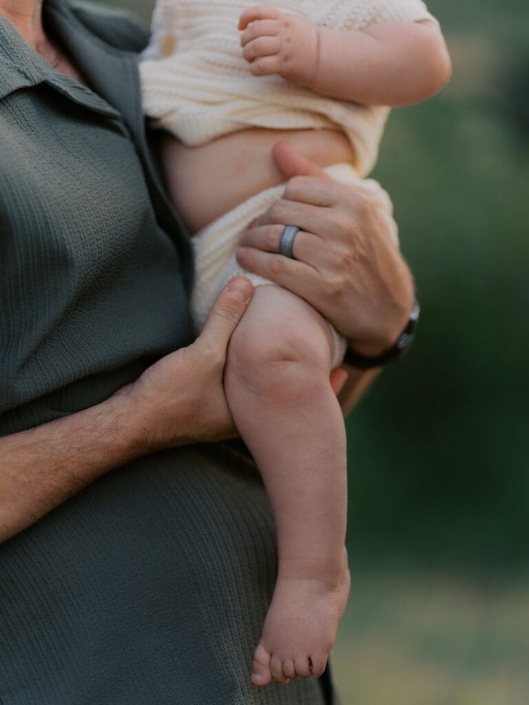 Close-up of father's hands holding baby's chubby legs and feet during Camarillo blue hour family photography session