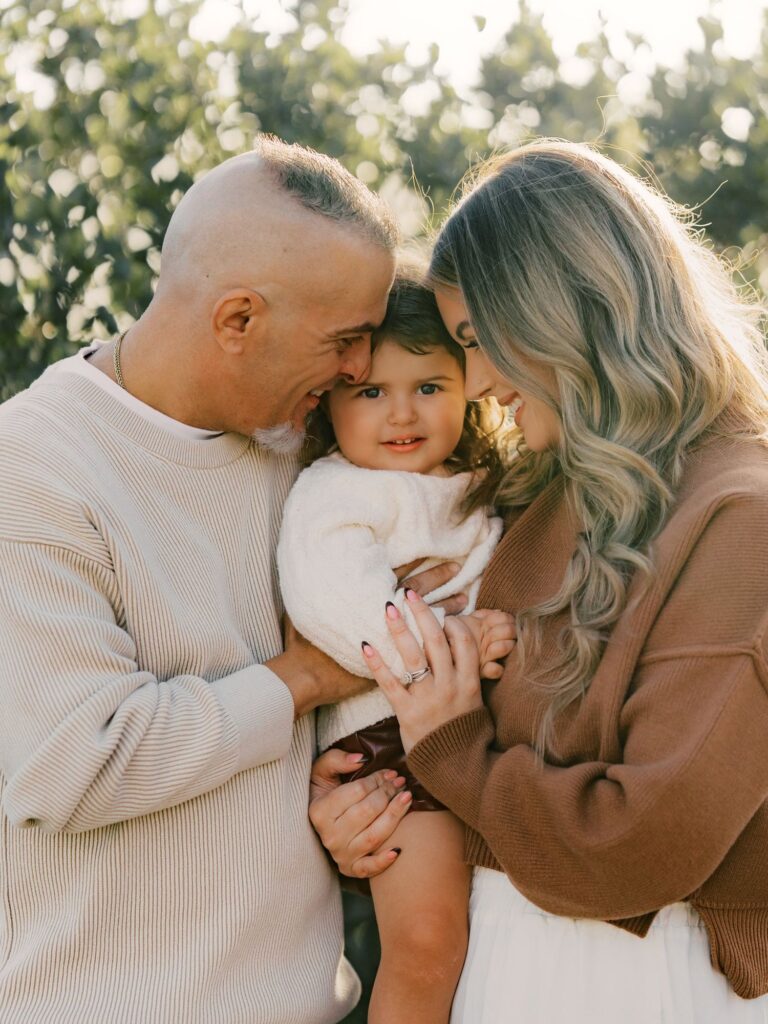 Parents snuggling their toddler daughter during a golden hour family session in Thousand Oaks, CA
